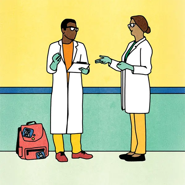Two scientists in lab coats and gloves discuss research in a hallway.